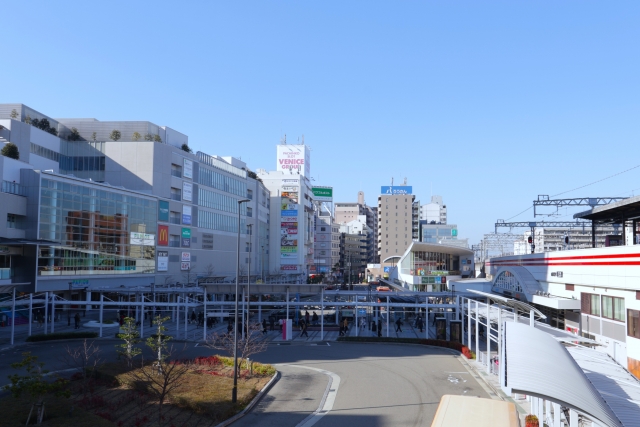 An urban station area with buildings and a pedestrian deck under a clear sky