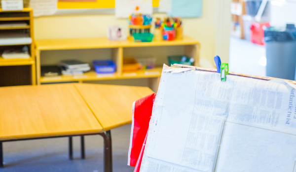 A classroom interior with tables and storage shelves, with a project board in the foreground