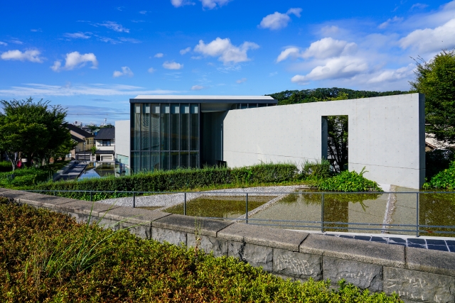 The Himeji City Museum of Literature under a blue sky, featuring concrete architecture and a reflecting pool