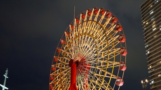 An illuminated ferris wheel at night in a harbor area