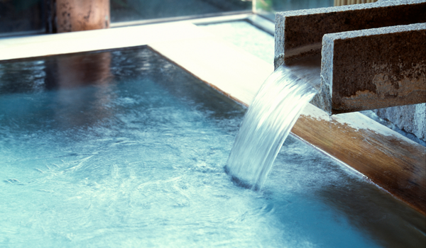 A close-up of hot spring water flowing into a bath