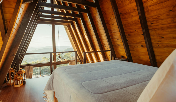 An A-frame lodge-style bedroom with large windows overlooking the mountains