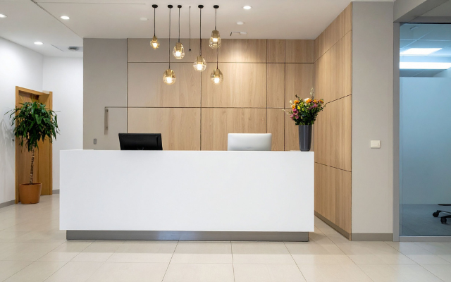 A modern reception desk with wooden walls and pendant lights