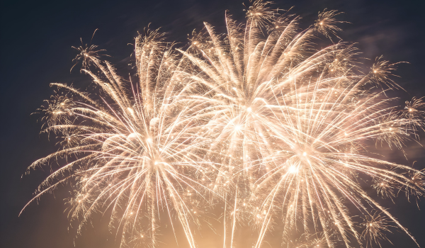 A close-up of golden fireworks bursting in the night sky