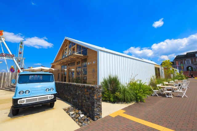 A wooden building with terrace seating at Kobe Fruit Flower Park Ozo under a clear blue sky