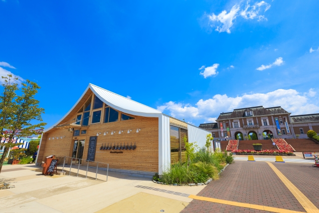 A wooden building and open plaza at Kobe Fruit Flower Park Ozo on a sunny day