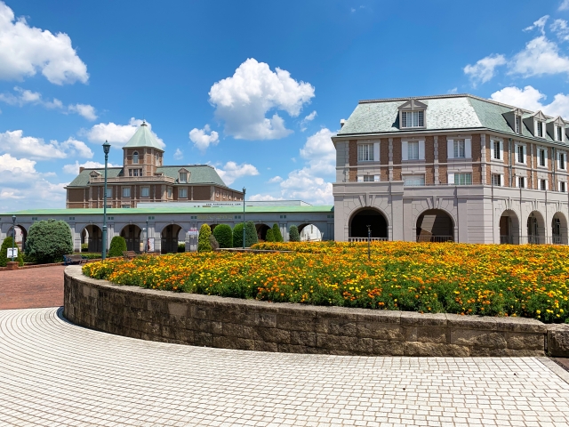 European-style buildings and colorful flowerbeds at Kobe Fruit Flower Park Ozo under a blue sky