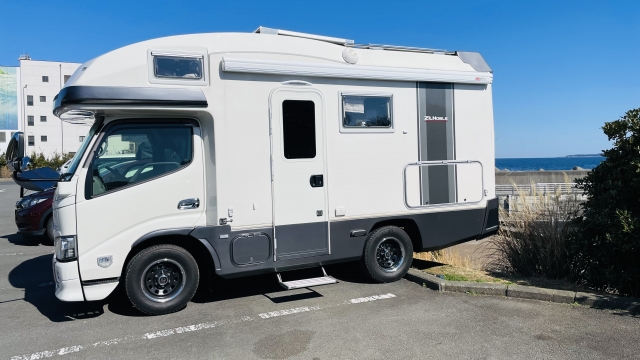 A white motorhome parked near the seaside on a sunny day