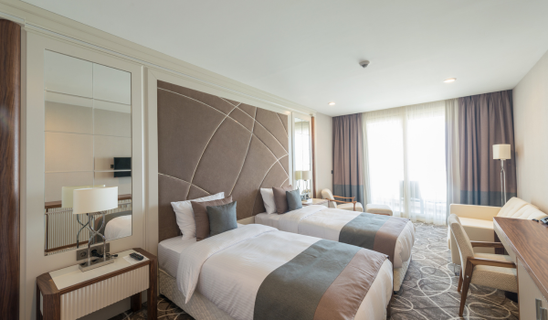 A modern twin hotel room with two white beds and a large window