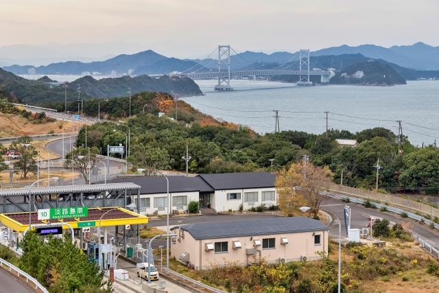 A view near Awajishima-Minami Interchange with roads and buildings, and a bridge over the strait in the distance