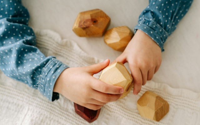 A child holding wooden balancing blocks