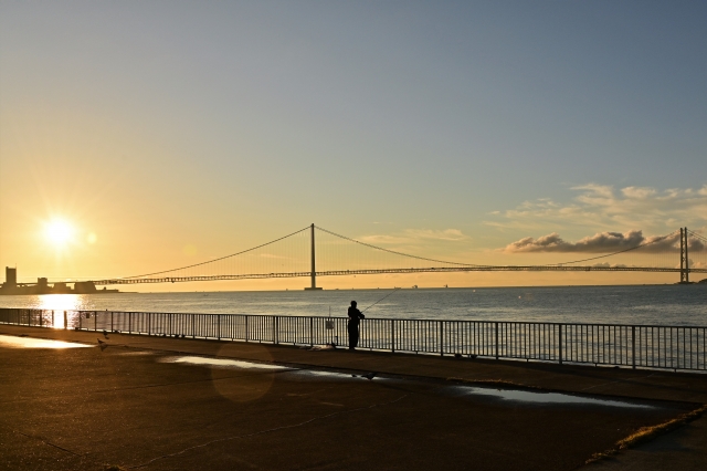 淡路島の夕日に染まる海と明石海峡大橋
